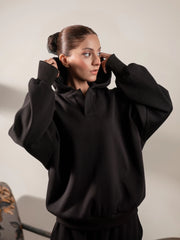 Front three-quarter view of the Garconne black hoodie, with the model raising both arms to show its roomy sleeves and oversized shape.
