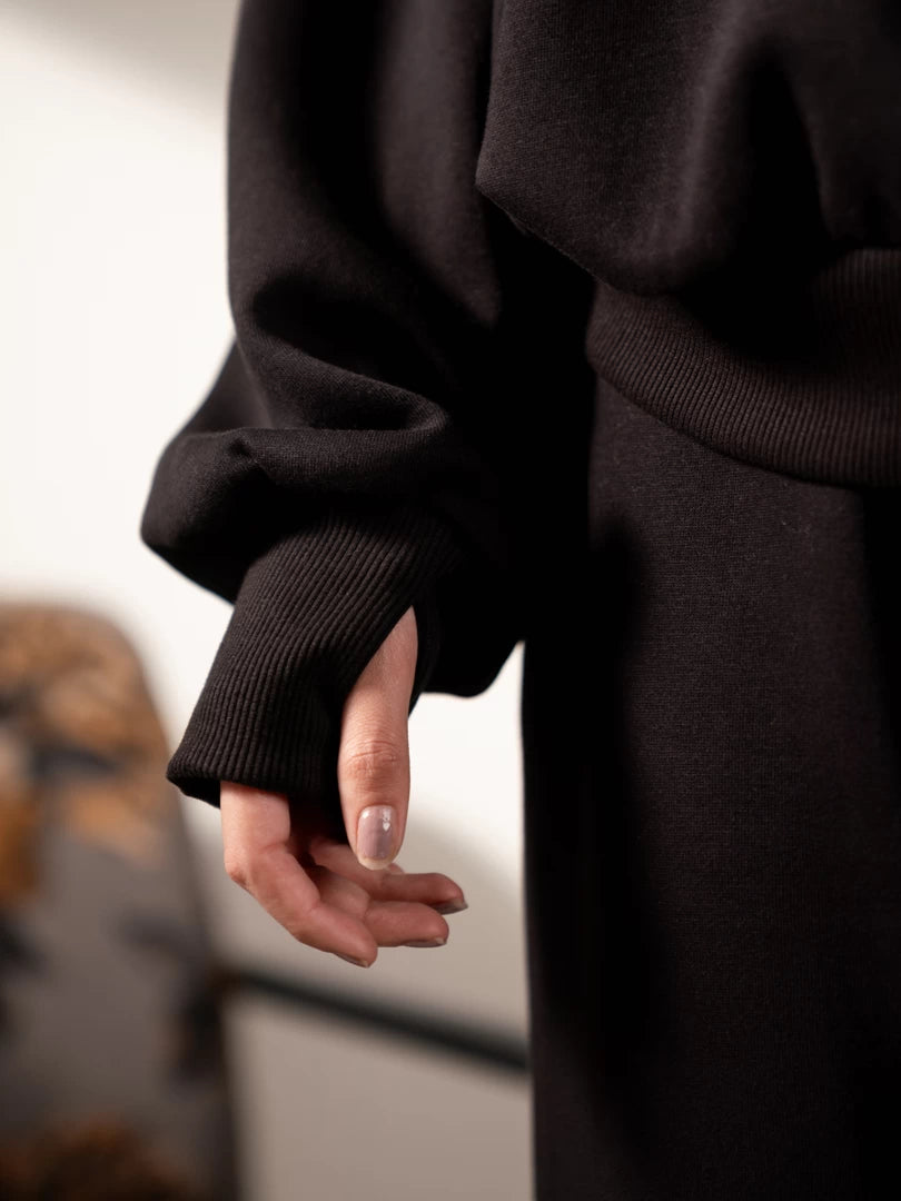 Close-up of the Garconne Black hoodie's extended sleeve cuff with a thumb hole, worn over the model's hand.