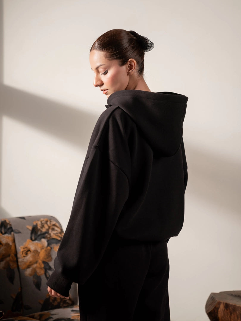Back three-quarter view of the Garconne oversized hoodie in Black, showing the hood, dropped shoulders and relaxed back fit.