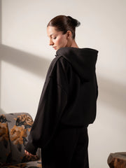 Back three-quarter view of the Garconne oversized hoodie in Black, showing the hood, dropped shoulders and relaxed back fit.