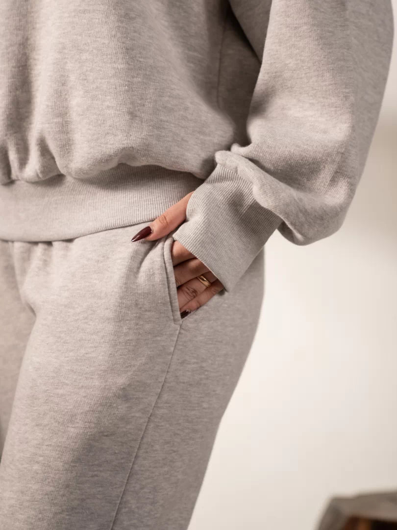 Detail of the Garconne Heather Grey oversized hoodie's front pocket, with the model's hand tucked into the soft fleece fabric.