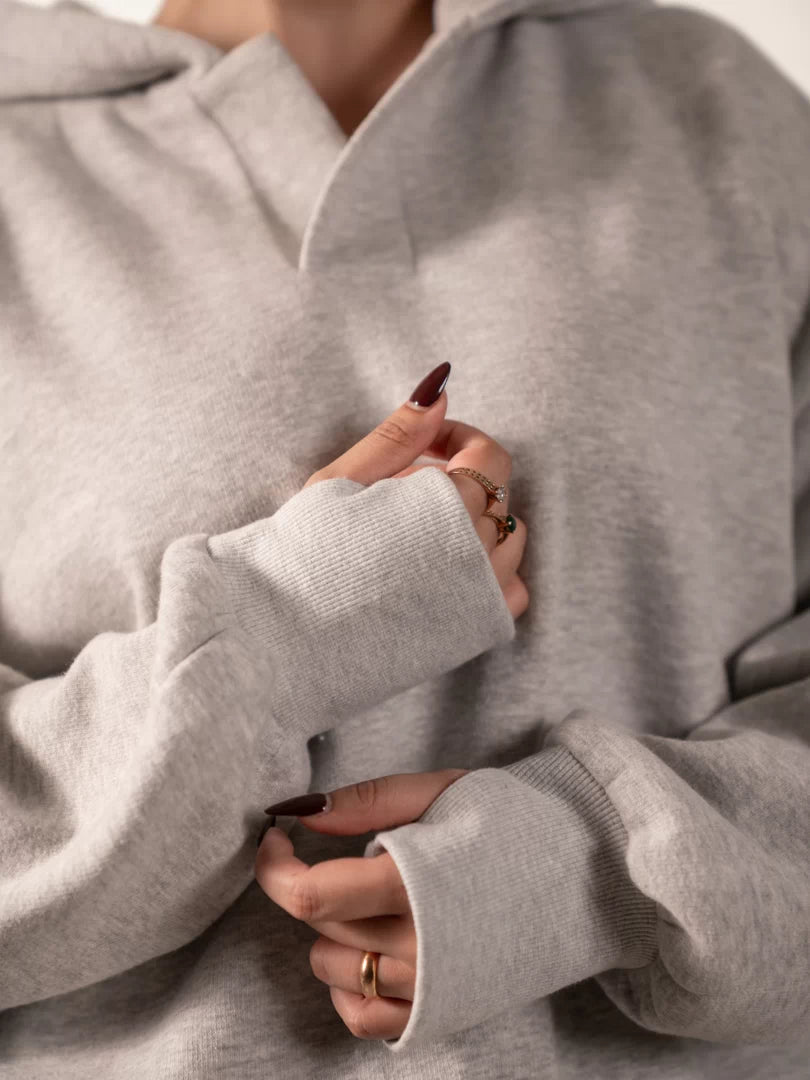 Close-up of the Garconne Heather Grey hoodie's extended sleeve cuff, showing the thumb-hole detail worn over the model's hand.