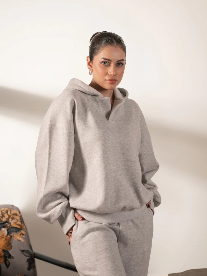 Model wearing the Garconne oversized hoodie in Heather Grey, with hands in the front pocket and a relaxed, loose-fitting shape.