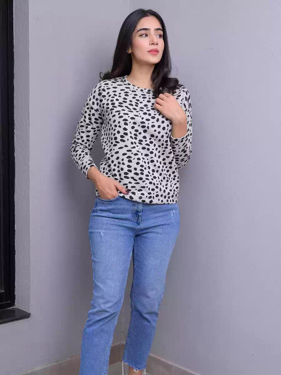 Model wearing Coastline's Heather Grey animal print sweatshirt with blue denim jeans, standing with one hand near her chest.