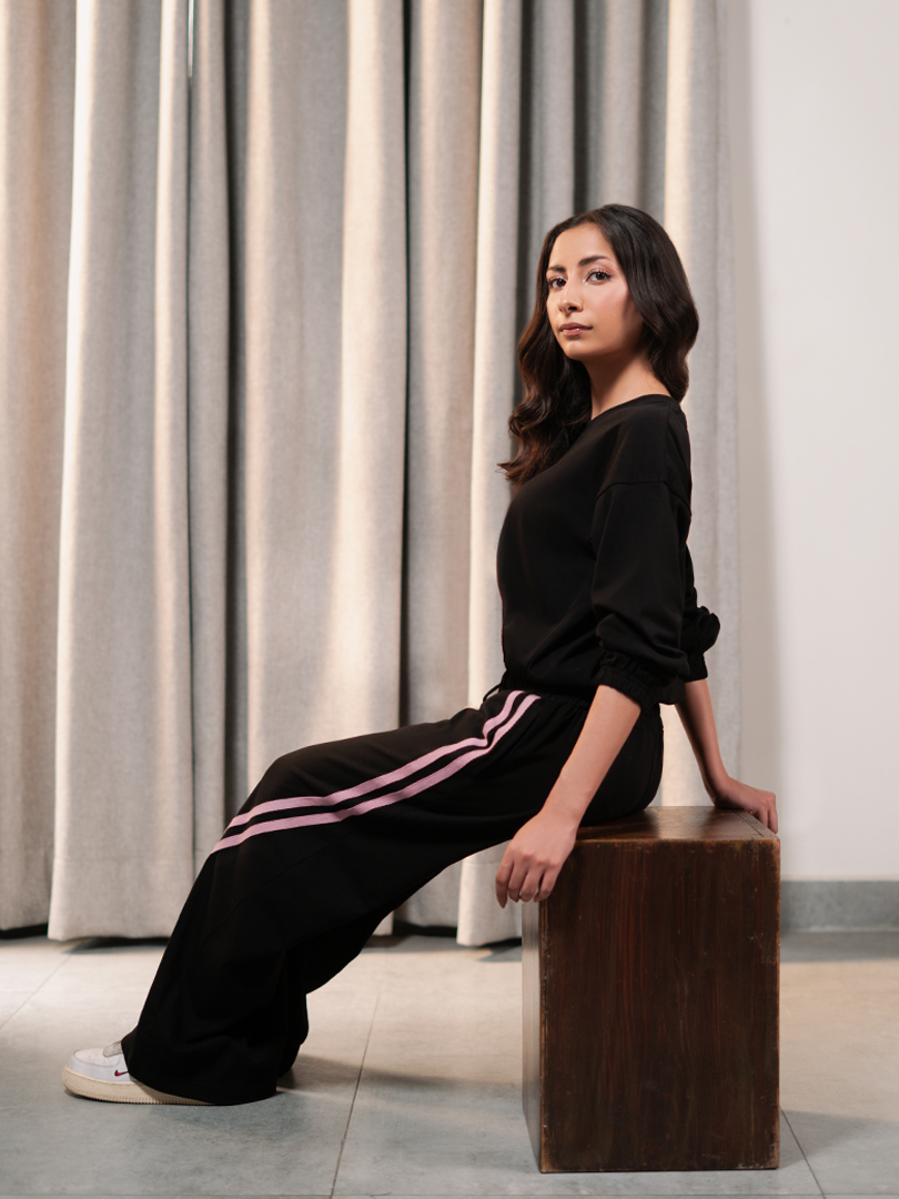 Seated model wearing the Indie Black summer co-ord set with a relaxed top and matching striped trousers