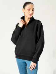 Model wearing the Kai American oversized black quarter-zip sweatshirt, holding its standing collar with one hand.