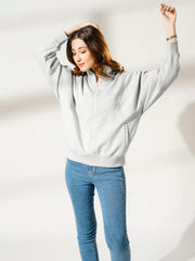 Back view of the Kai Heather Grey oversized sweatshirt with the model raising her arms, showing its loose sleeves and back fit.