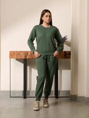 Model wearing the Kiwi green garment-dyed sweat set with a crew-neck sweatshirt and matching trousers, with both hands near the pockets.