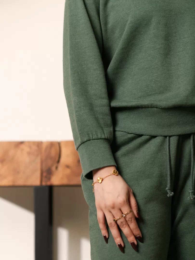 Close-up of the Kiwi green sweatshirt showing its ribbed sleeve cuff, hem and garment-dyed finish.