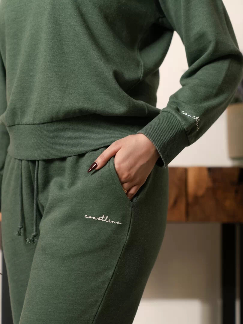 Close-up of the Kiwi green trousers showing the waistband, side pocket and garment-dyed colour variation.