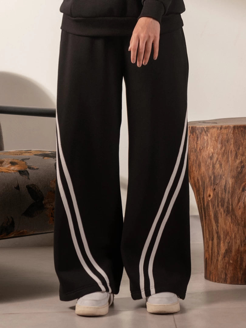 Front view of the Lana Black wide-leg trousers showing light contrast stripes running diagonally toward the hems.