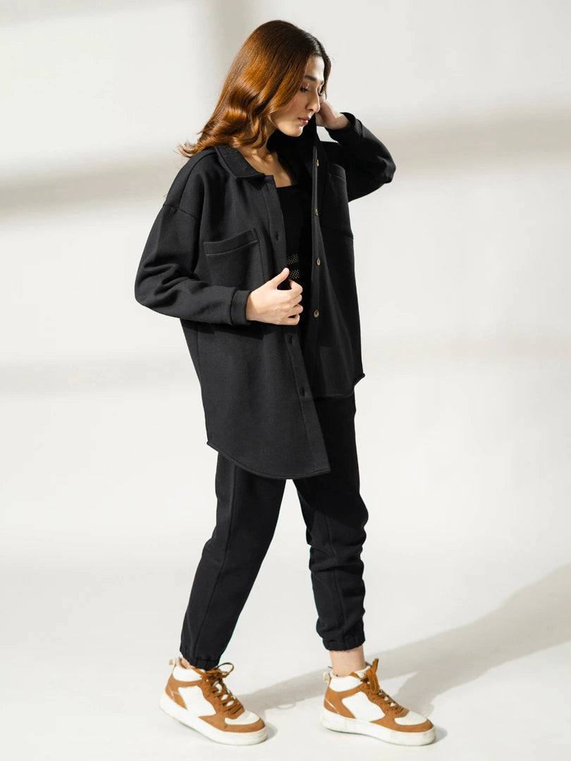 Model stepping forward in the Maru black longline shacket, showing the loose fit and side silhouette.