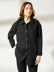 Closer front view of the Maru black shacket showing the collar, front pockets and button opening, with one hand at the hip.