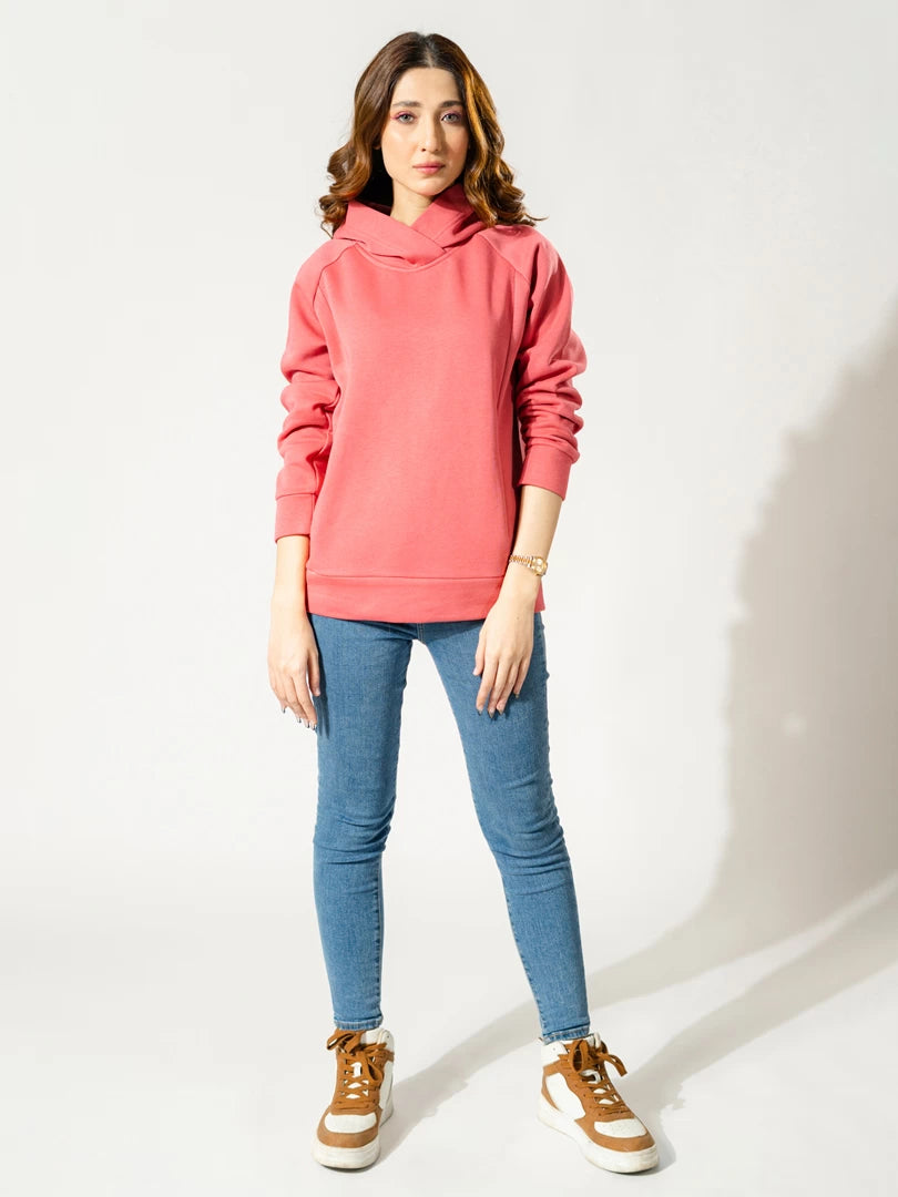 Full-length front view of the Naia fleece pullover hoodie in Lychee Pink, worn with blue jeans and tan sneakers.
