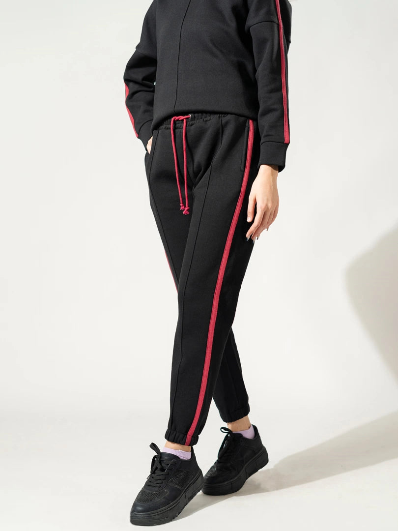 Closer view of the Ora black trousers showing the contrasting tape and cut-and-sew panel detailing.