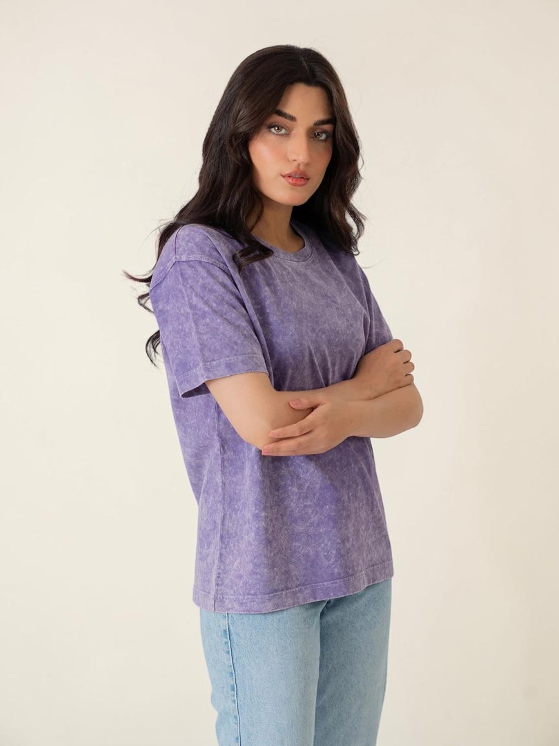 Front view of the Sage Purple oversized cotton tee with a mineral-washed finish, worn by a model with folded arms.