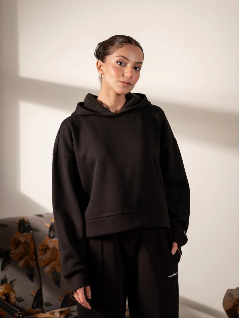 Closer front view of the Soho black boxy hoodie showing the hood neckline and loose sleeves.