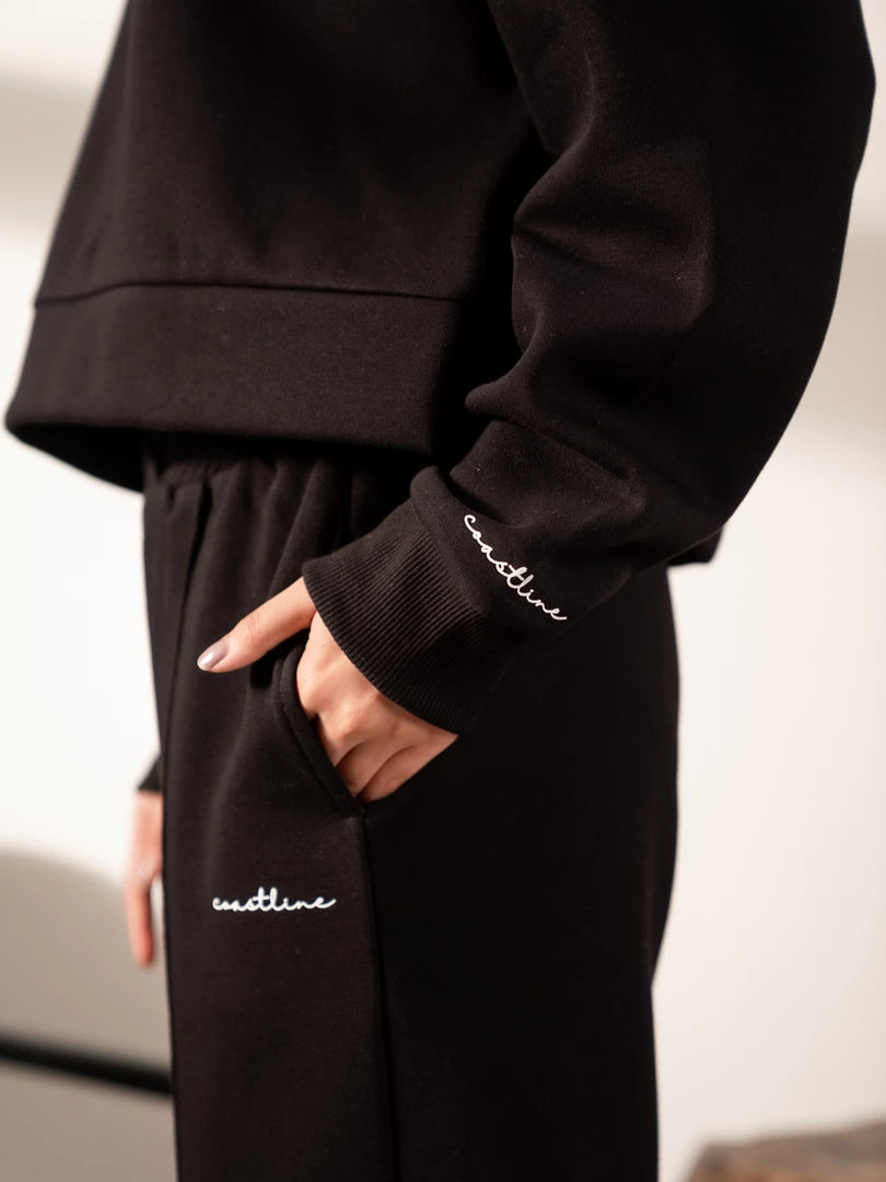 Close-up of the Soho black set showing the ribbed sleeve cuff, hoodie hem and upper trouser detail.