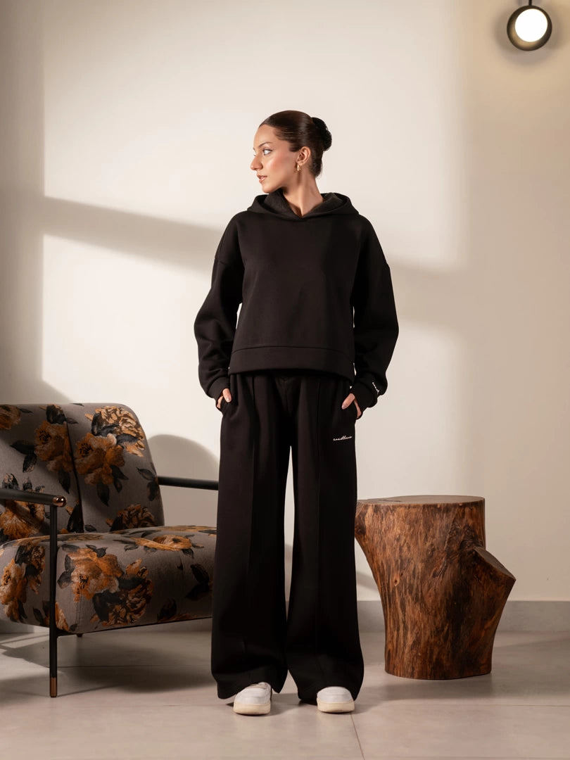 Model wearing the Soho black hoodie and wide-leg trouser set, with her head turned to the side.