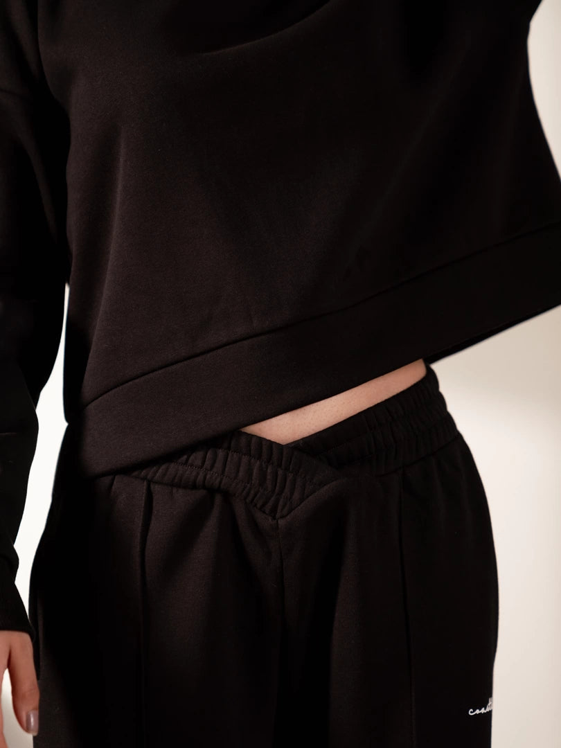 Close-up of the Soho black trouser waistband beneath the raised hoodie hem.