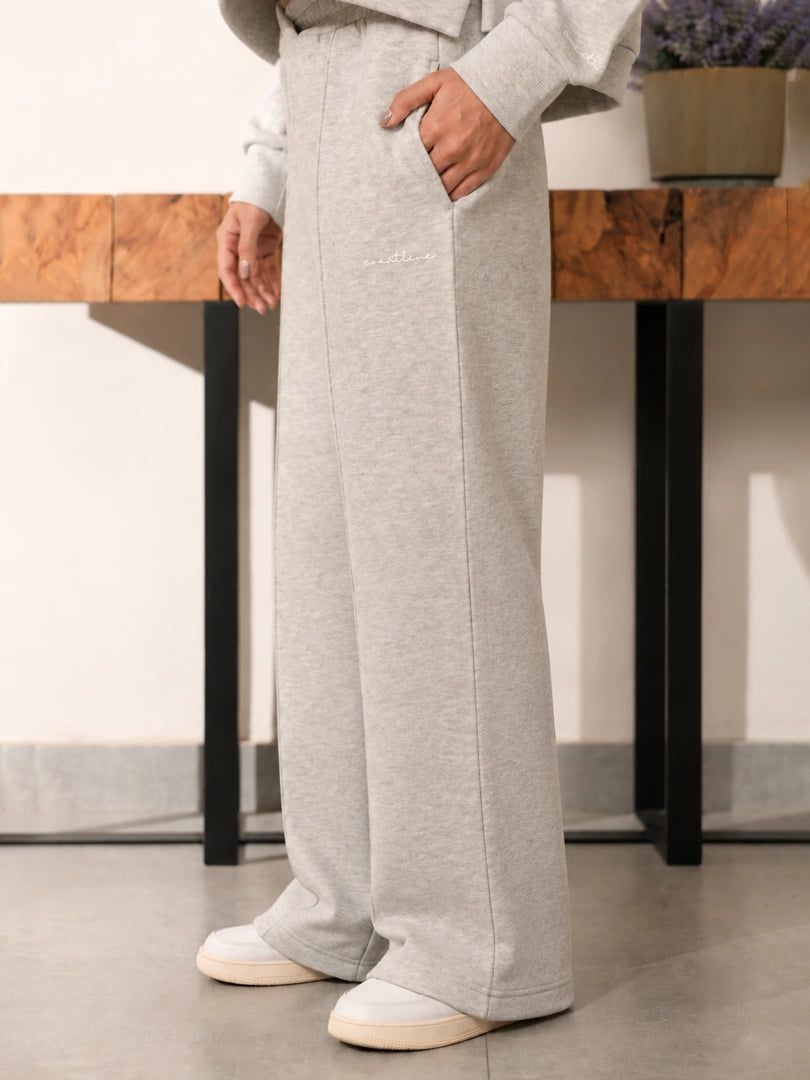 Full-length front view of the Soho grey fleece trousers showing their wide-leg fit and hems over white sneakers.