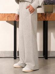 Full-length front view of the Soho grey fleece trousers showing their wide-leg fit and hems over white sneakers.