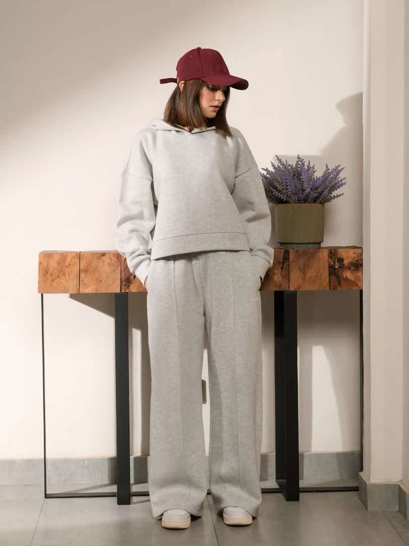 Model wearing the Soho Heather Grey cotton fleece hoodie set with a boxy hoodie and wide-leg trousers, styled with a burgundy cap.