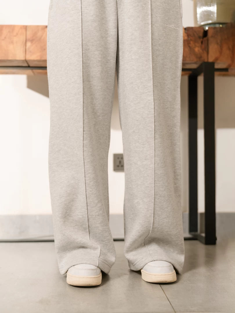 Closer view of the Soho Heather Grey wide-leg trousers showing the relaxed leg shape and hems above white trainers.