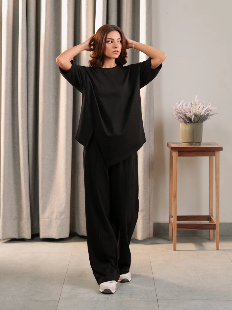 Model wearing the Sorelle black oversized summer co-ord set with a loose top and wide-leg trousers, with both hands raised.