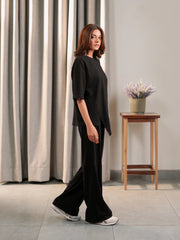 Side view of the Sorelle black co-ord set showing the loose top, side slit and wide-leg trousers.