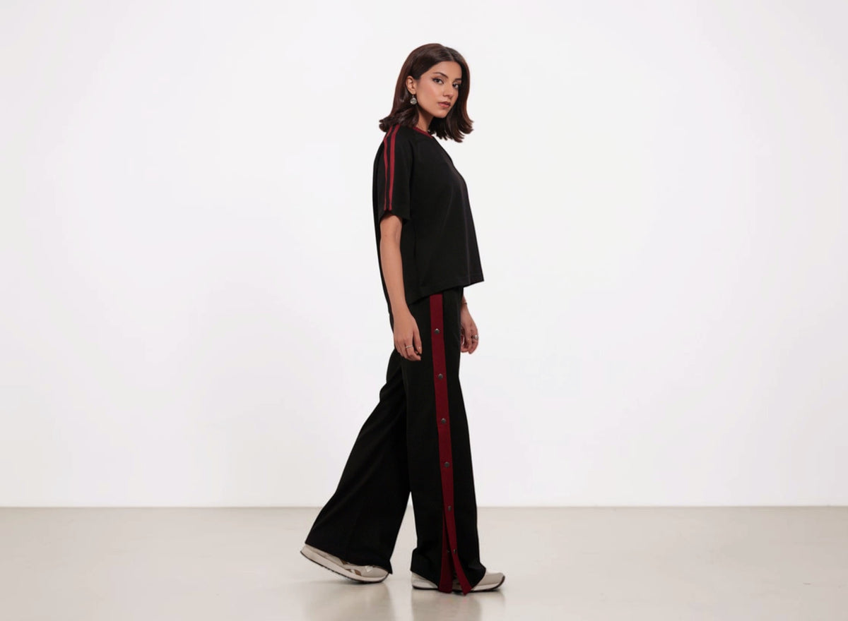 Woman wearing a black outfit with red stripes on a white background