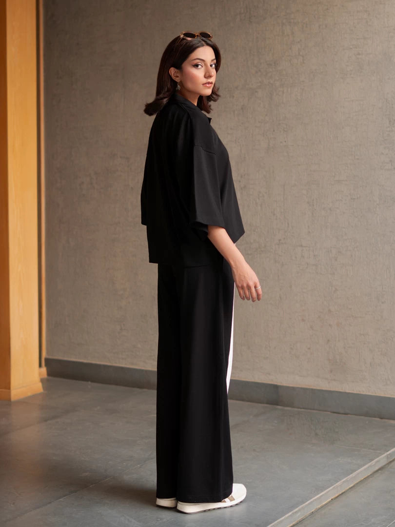Side view of the Zane black co-ord set showing the loose top, dropped shoulders and wide-leg trouser silhouette.