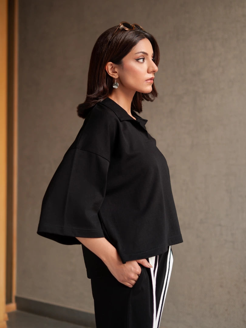 Closer view of the Zane black top showing its collar, open placket, wide sleeves and relaxed boxy fit.