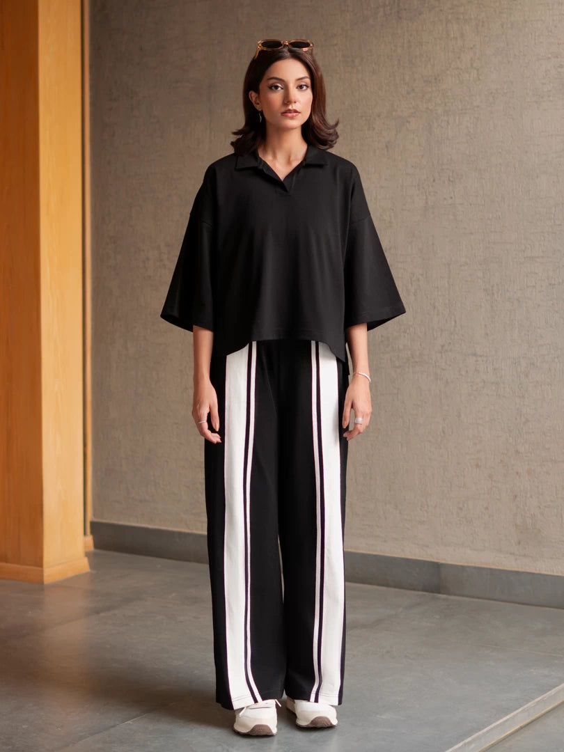 Front view of the Zane black summer co-ord set showing the boxy top and contrasting stripes on the wide-leg trousers.