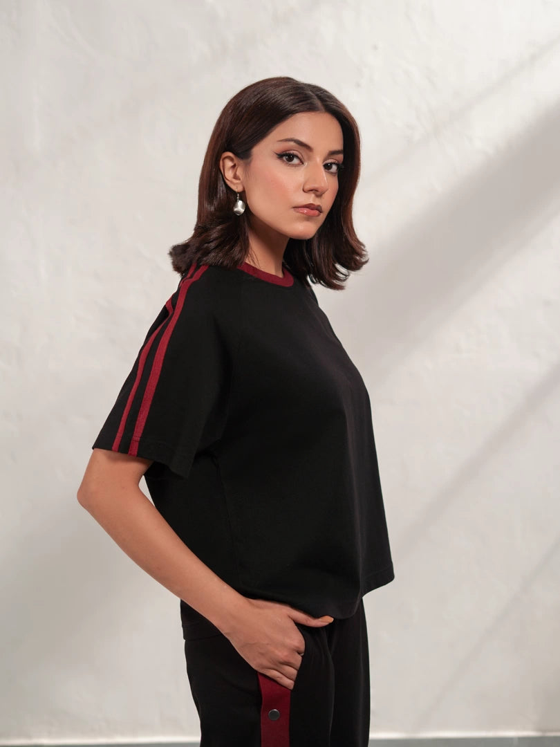 Closer view of the Zoey Black short-sleeve top showing its relaxed shape and contrast tape along the shoulder and sleeve.