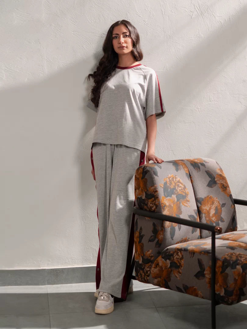 Angled view of the Zoey Heather Grey two-piece summer outfit with contrasting red trim along the sleeves and trousers.