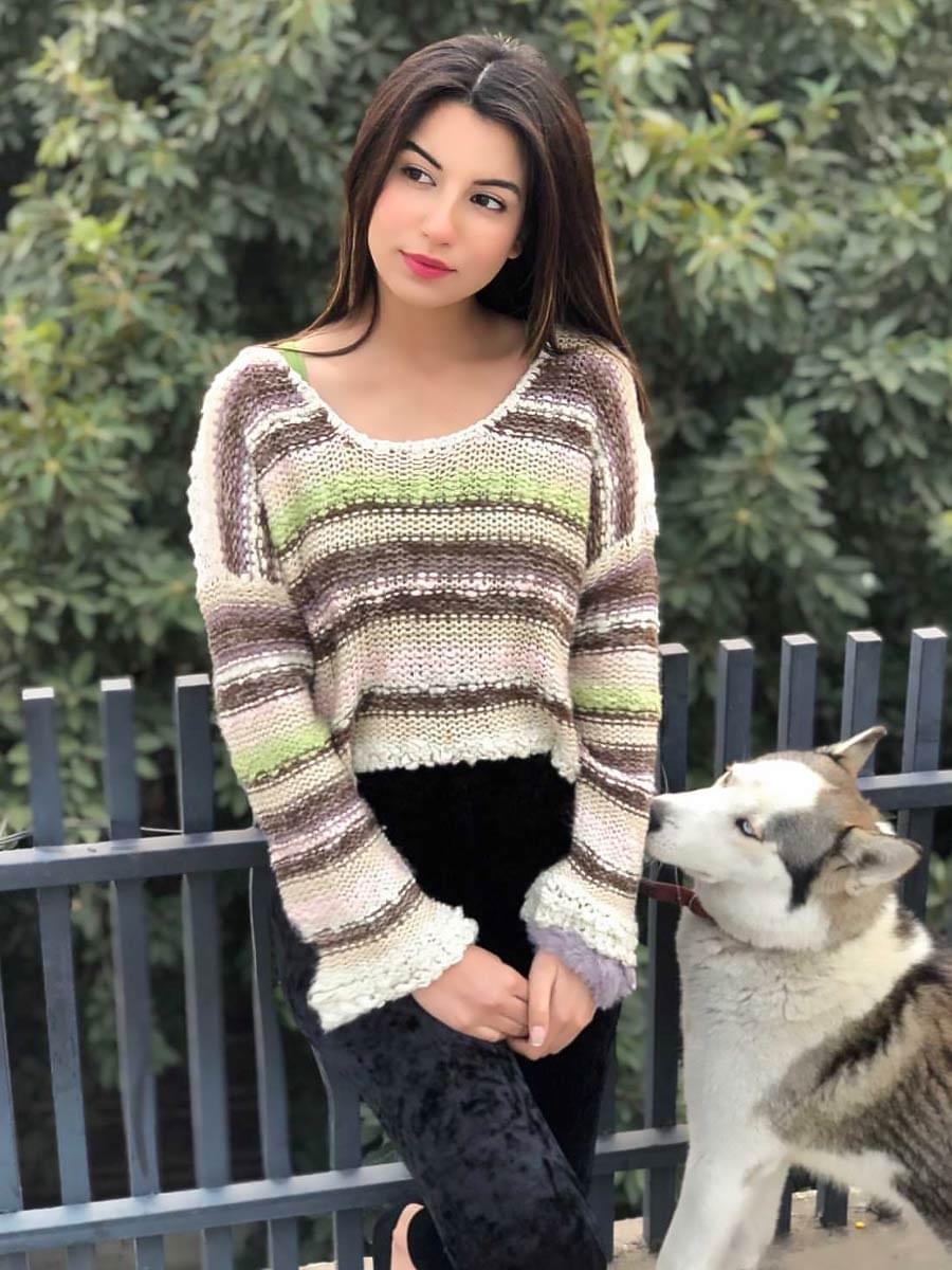Model wearing Coastline's Cropped Multicolor Sweater with striped multicolor knit, styled with black trousers outdoors.