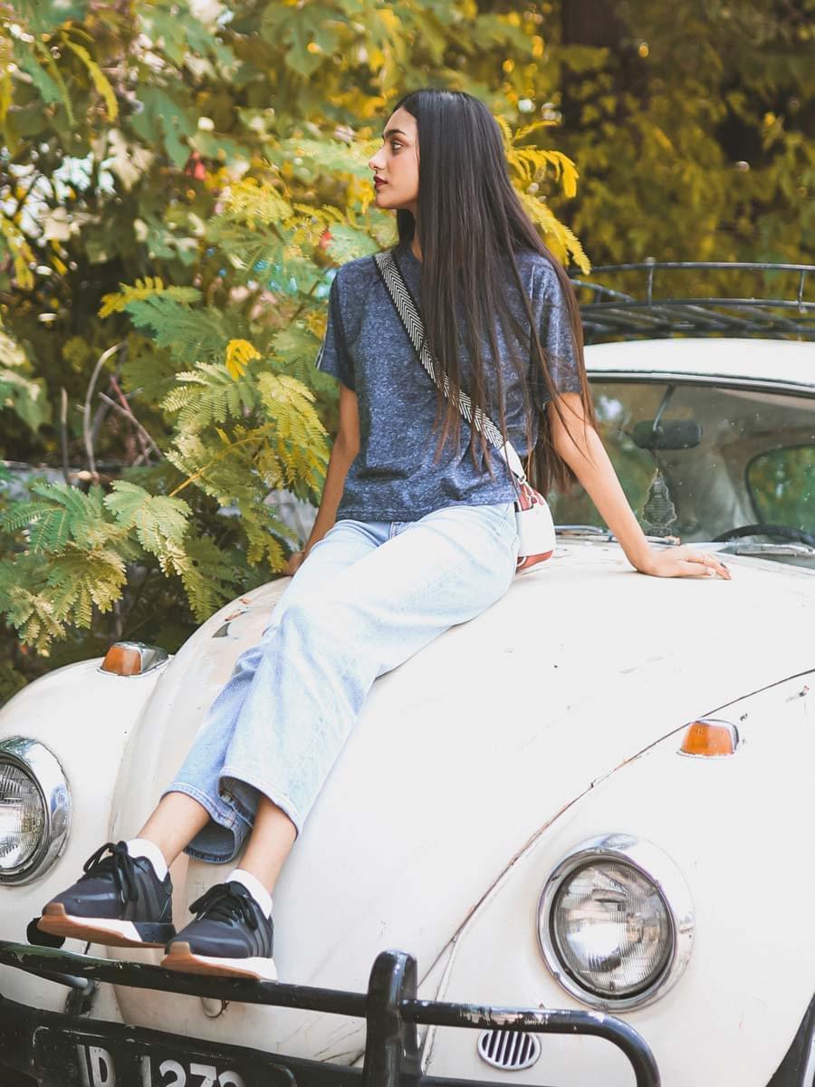 Full outfit view of Coastline's Heritage Fashion Tee in Pixel Blue, styled with light-wash denim as the model sits on a white vintage car.