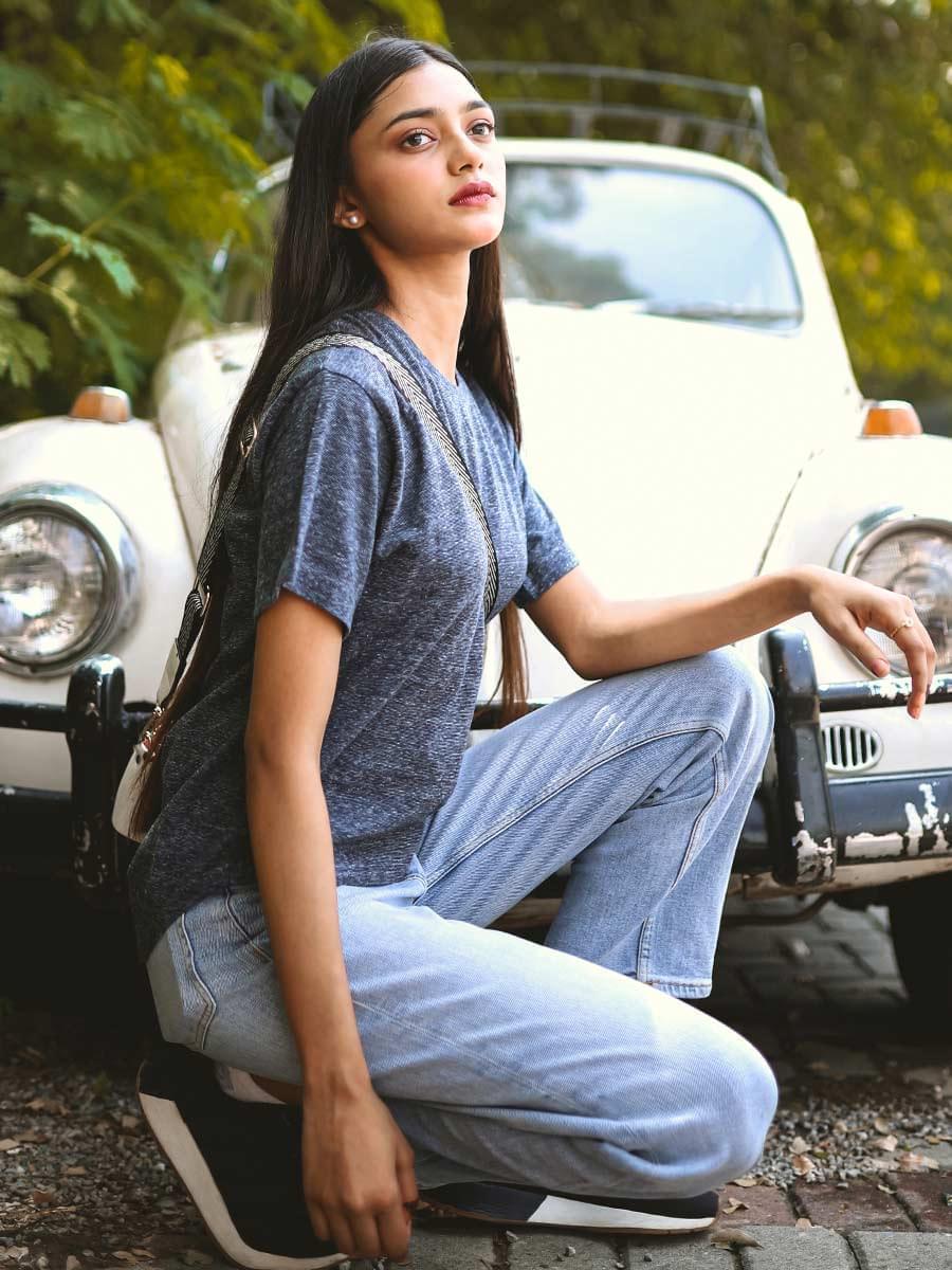 Seated outdoor view of the Heritage Fashion Tee in Pixel Blue, showing its oversized cut and textured cotton jersey fabric.