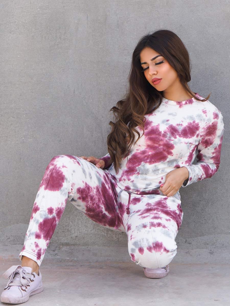 Seated model wearing the Ocean Drive Purple two-piece tie dye set with a long-sleeve top and matching trousers